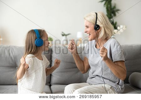 Happy Grandmother And Granddaughter Listening To Music In Headph