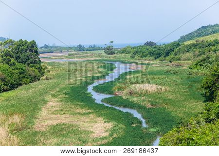 River Waters Winding Through Tropical Vegetation Towards Lagoon With Distant Ocean Coastline Landsca