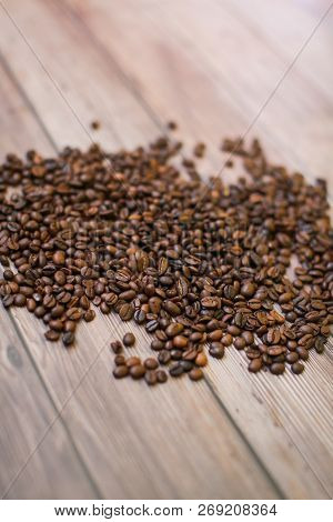 Close Up Coffee Beans Scattered On Wood Background In Selective Focus