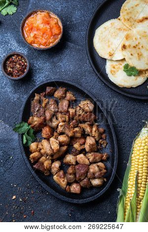 Colombian Food. Fried Pork Chicharron, Arepas And Colombian Tomato Sauce. Top View. Black Background