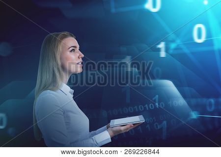 Side View Of Inspired Young Businesswoman Holding Tablet Computer Standing Over Dark Blue Background
