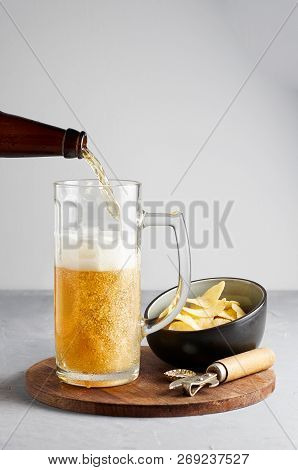 Lager Beer Pouring In Glass And Bottle With Potato Chips On Gray Concrete Background