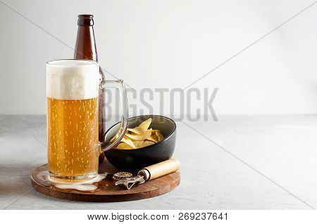 Lager Beer In Glass And Bottle With Potato Chips On Gray Concrete Background