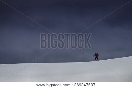 Lone Skier Walking On Fresh Snow Across The Horizon