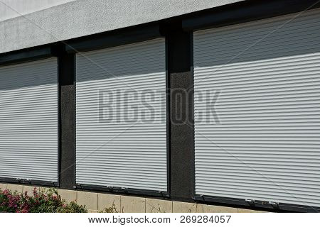 Three Windows Covered With White Plastic Shutters On The Wall Of The House