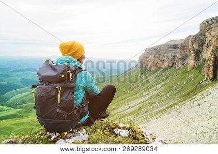 Sitting Back Girl Traveler In A Yellow Hat And A Pair Of Sunglasses Ssitting At The Foot Of Epic Roc