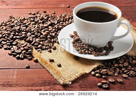weiße Tasse mit Kaffeebohnen auf den Holztisch