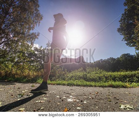 Slim Body Guy Runs On Path With Fallen Leaves. Warm Day For Outdoor Excersising.