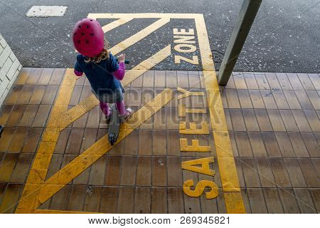 Young Girl In Pink Outfit And Pink Helmet Riding A Kick-scooter Across The Railway Line