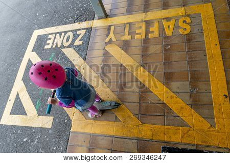 Young Girl In Pink Outfit And Pink Helmet Riding A Kick-scooter Across The Railway Line