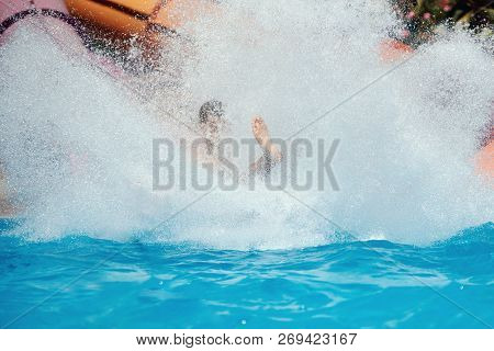 Man Having Fun In Aqua Park. He Is Sliding Down From The Flume. Thera Are A Lot Of Splashes Aroun Hi