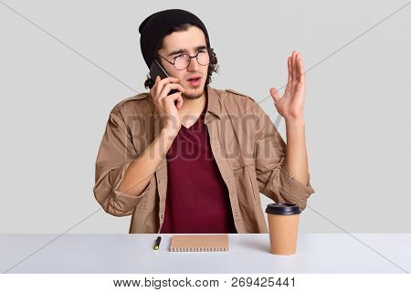 Emotional Displeased Guy Has Telephone Coversation, Raises Hand, Discusses Something Actively, Drink