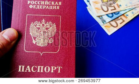 Hands Holding Passports On  Blue Background. Citizenship Of Estonia And Russia. Citizenship Of Europ