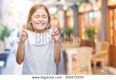Young beautiful girl over isolated background smiling crossing fingers with hope and eyes closed. Luck and superstitious concept.