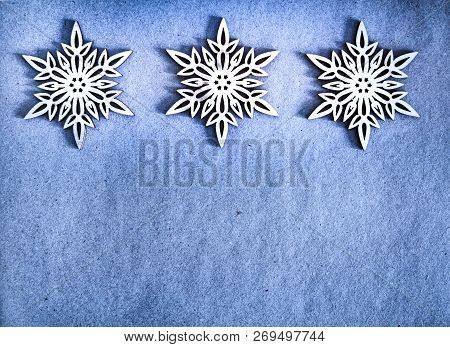 Three White Wooden Snowflakes On Blue Craft Paper