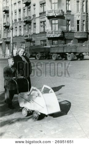 Vintage photo of mother with a son and a baby in pushchair (1954)