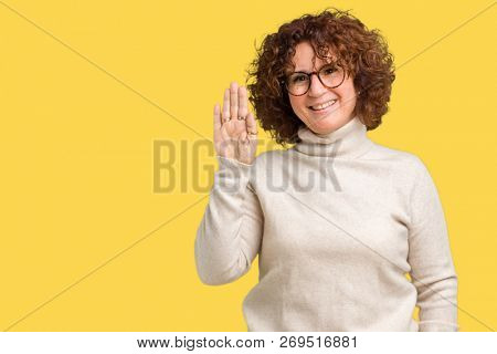 Beautiful middle ager senior woman wearing turtleneck sweater and glasses over isolated background Waiving saying hello happy and smiling, friendly welcome gesture
