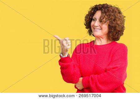 Beautiful middle ager senior woman red winter sweater over isolated background Looking proud, smiling doing thumbs up gesture to the side