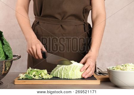 Woman Cutting Savoy Cabbage On Board At Table