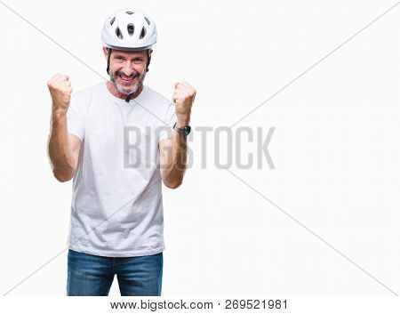 Middle age senior hoary cyclist man wearing bike safety helment isolated background celebrating surprised and amazed for success with arms raised and open eyes. Winner concept.