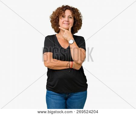 Beautiful middle ager senior woman over isolated background looking confident at the camera with smile with crossed arms and hand raised on chin. Thinking positive.