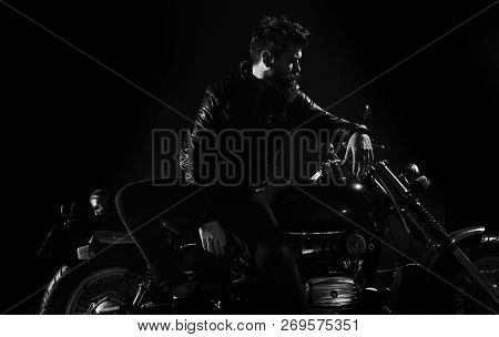 Man With Beard, Biker In Leather Jacket Lean On Motor Bike In Darkness, Black Background. Biker Cult