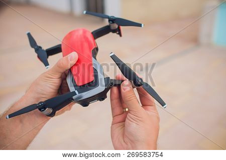 Red Drone Catching Control By Man Hands. Lays Out Propellers