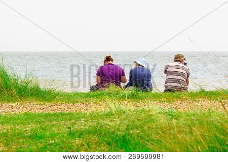 Suffolk, Uk - September 7, 18 - Back View Of A Family Sitting On Minsmere Beach