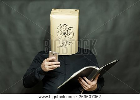 Emotion Concept. A Man Is Reading A Book. The Phone Rings. Facial Expression Is Inconvenience And Cu