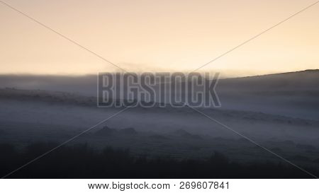 Stunning Foggy Sunrise Landscape Over The Tors In Dartmoor Revealing Peaks Through The Mist