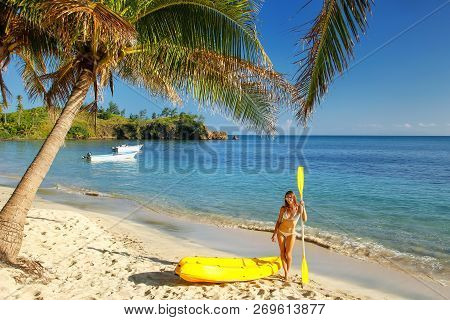 Young Woman In Bikini Standing On A Sandy Beach With Sea Kayak And Paddle, Nacula Island, Fiji