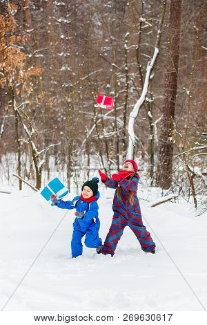 Happy Children In A Winter Snow-covered Forest With Gift Boxes.