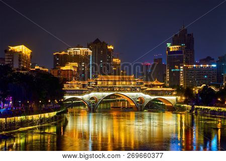 Famous landmark of Chengdu - Anshun bridge over Jin River illuminated at night with modern skyscrapers in background, Chengdu, Sichuan , China