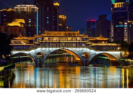 Famous landmark of Chengdu - Anshun bridge over Jin River illuminated at night with modern skyscrapers in background, Chengdu, Sichuan , China