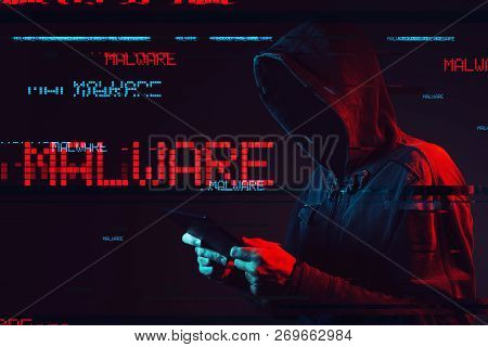 Malware Concept With Faceless Hooded Male Person Using Tablet Computer, Low Key Red And Blue Lit Ima
