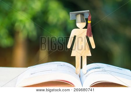 Back To School Concept, Woman Sign Wood With Graduation Cap On Open Textbook With Light Green Backgr