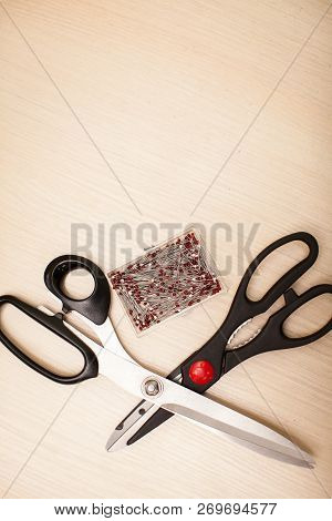 On The Cutting Table Lie Scissors And Pins. Work Place Of Seamstress. Topp View, Place For Text.