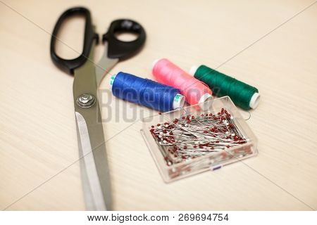 On The Cutting Table Lie Scissors, Thread And Pins. Work Place Of Seamstress. Topp View, Place For T