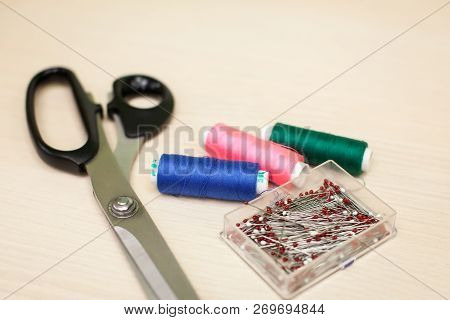On The Cutting Table Lie Scissors, Thread And Pins. Work Place Of Seamstress. Topp View, Place For T