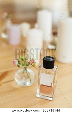 Bottle Of Perfume On Background Of Candles And Vase With Tiny Flowers