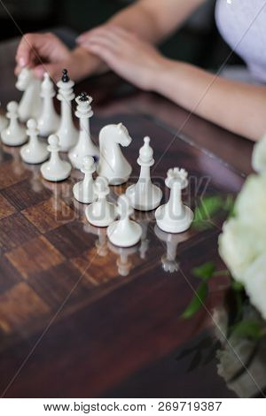 Picture Of White Chess Pieces On Chessboard And Woman Considering Making Move
