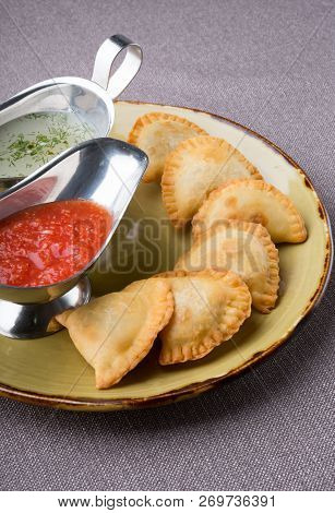 Small Pirogi Stuffed With Meat Served On A Plate With Sauces