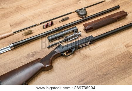 Disassembled Shotgun Parts And Cleaning Kit On The Wooden Background