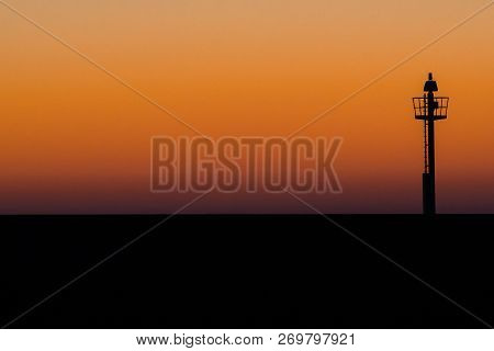 Abstract Photo Of A Light Signal Or Light Buoy Against A Brightly Colored Sky With Beautiful Intense