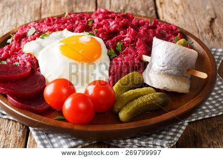 Northern German Labskaus Of Potatoes, Corned Beets And Beets With A Fried Egg, Pickles And Herring C