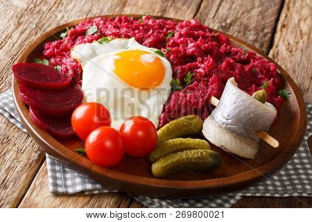 Home-made Labskaus Of Potato, Corned Beef And Beet Served With Fried Egg, Pickles And Rollmops Close