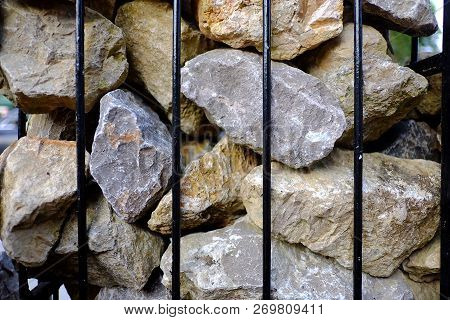 A Pile Of Big Rocks In A Black Metal Fence For Background Texture