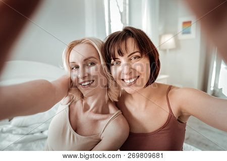 Contrast Blond And Brunet Ladies Making Selfie
