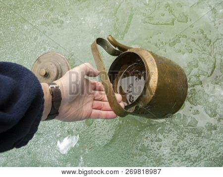 A Hand With Kettle Taking Water From An Ice Hole, Outdoor Close-up Shot