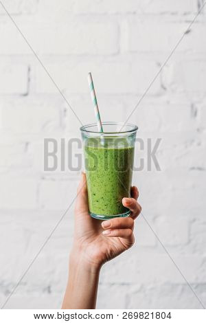 Female Hand Holding Glass With Green Organic Smoothie And Straw